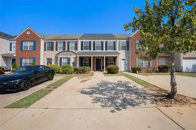 a view of a white house with a large tree in front of it