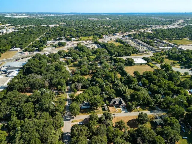 an aerial view of residential house with parking and trees