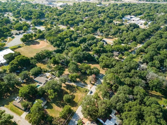 an aerial view of residential houses with outdoor space and trees