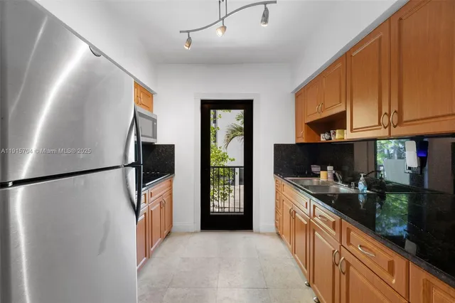 a kitchen with stainless steel appliances granite countertop a refrigerator a oven and a sink with cabinets