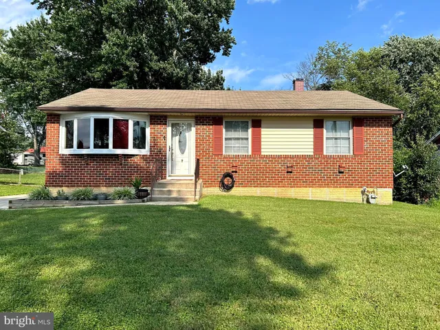 a front view of house with yard and trees in the background