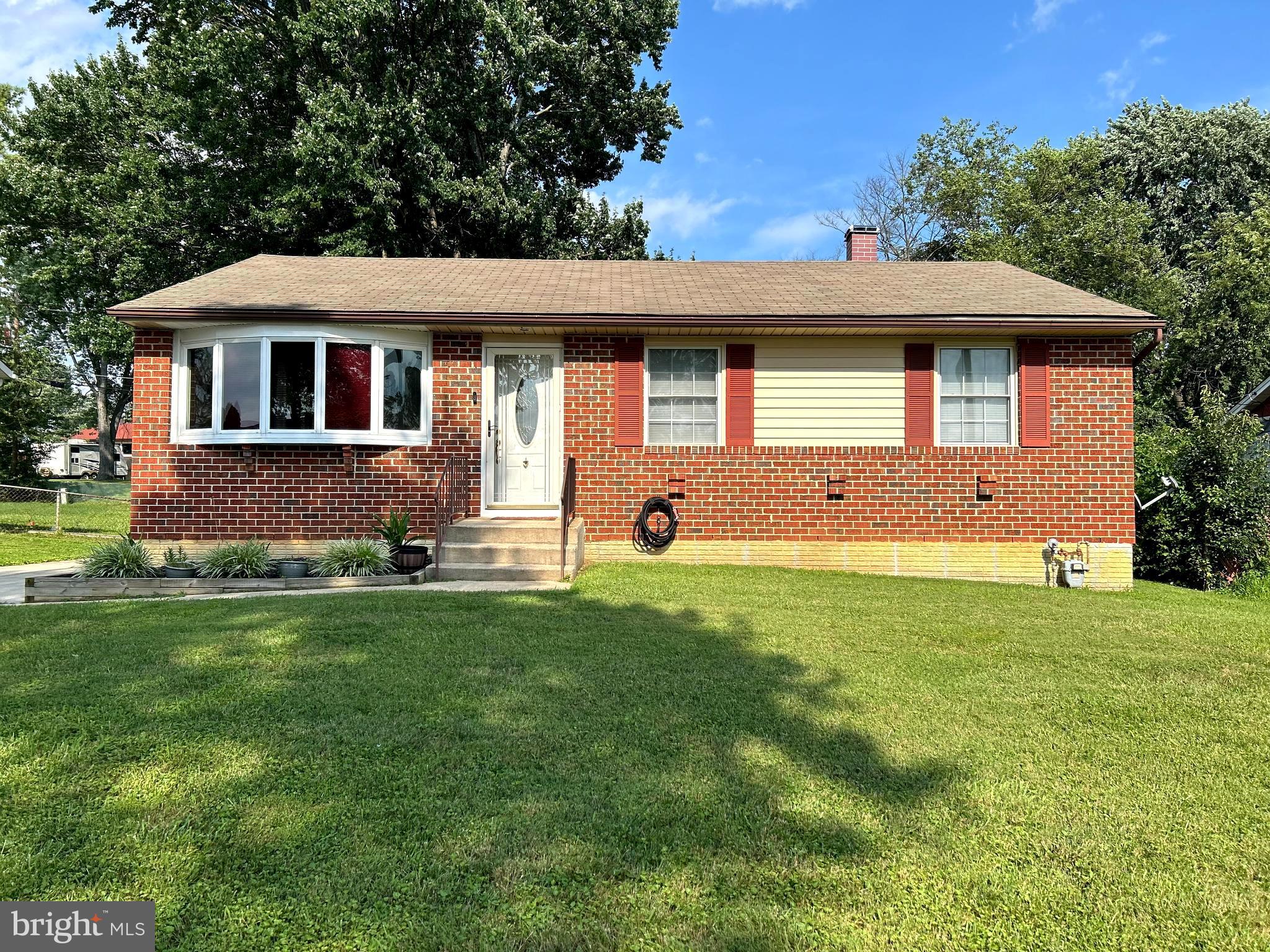 a front view of house with yard and trees in the background