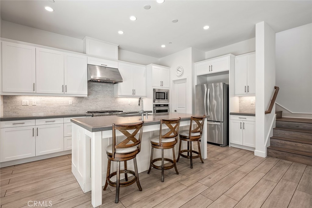 77 English Saddle Irvine, CA 92602 - Photo 12 of 35 a kitchen with stainless steel appliances granite countertop a table chairs stove refrigerator and cabinets