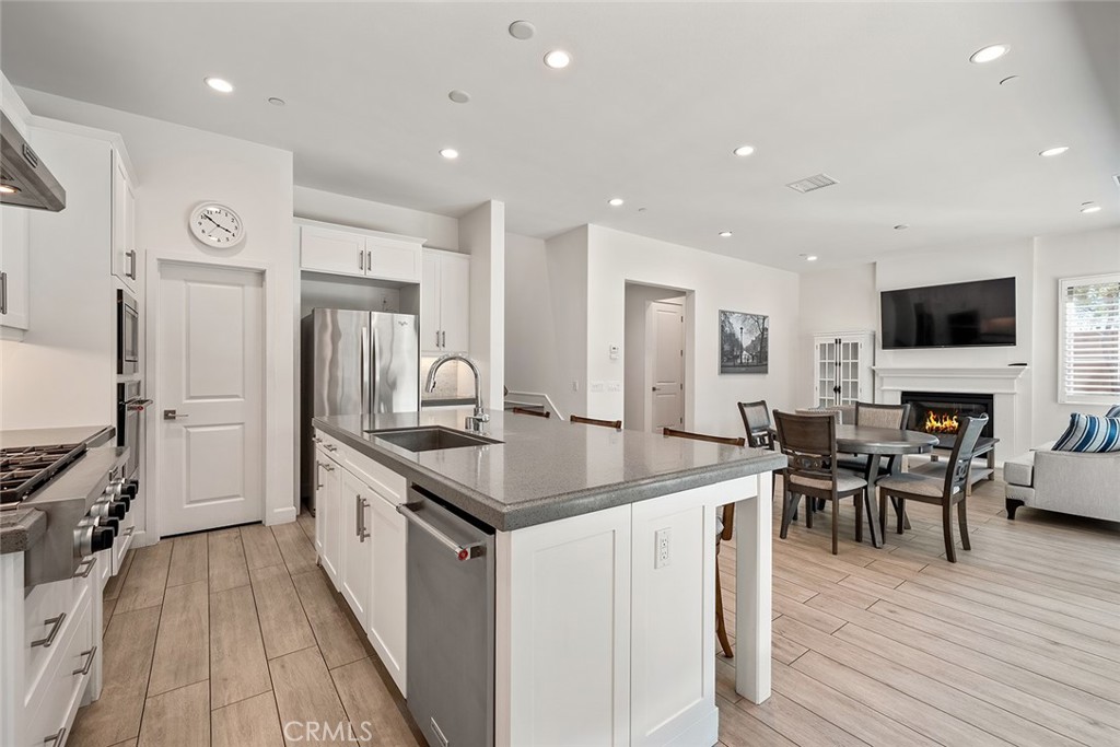 77 English Saddle Irvine, CA 92602 - Photo 14 of 35 a kitchen with stainless steel appliances granite countertop a stove top oven a sink dishwasher a dining table and chairs with wooden floor