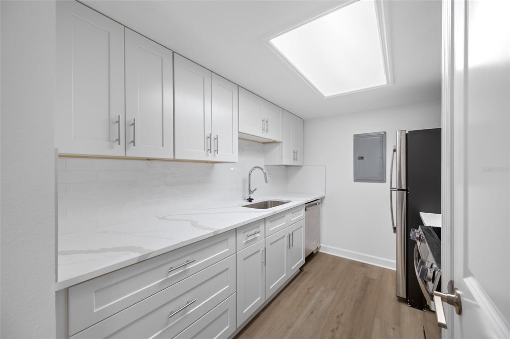8911 Blind Pass Road, Unit 114 St. Pete Beach, FL 33706 - Photo 21 of 43 a kitchen with a sink stainless steel appliances and cabinets