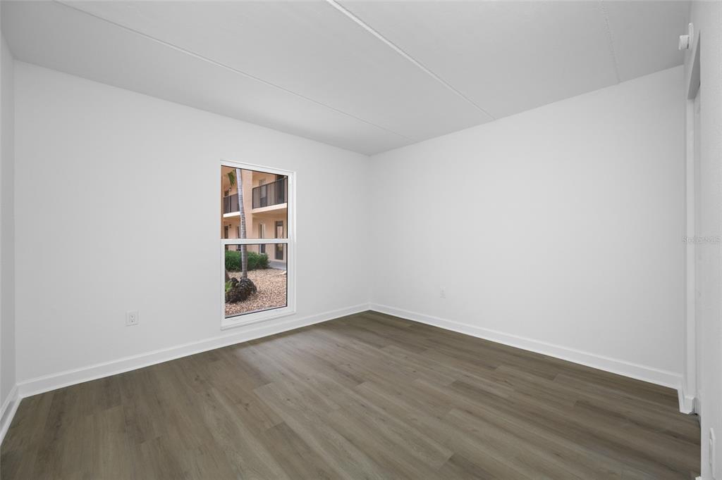 8911 Blind Pass Road, Unit 114 St. Pete Beach, FL 33706 - Photo 23 of 43 an empty room with wooden floor and windows