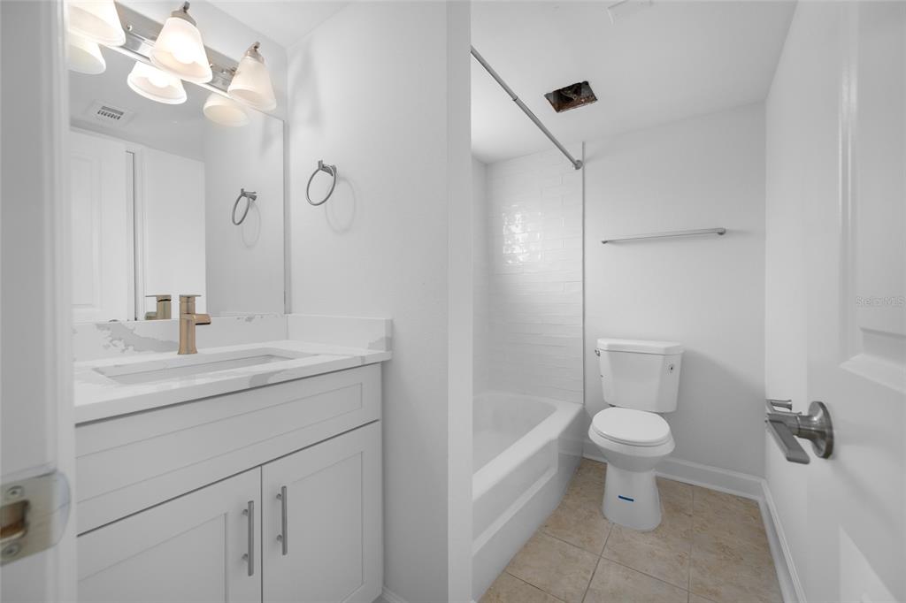 8911 Blind Pass Road, Unit 114 St. Pete Beach, FL 33706 - Photo 28 of 43 a bathroom with a sink a toilet and a mirror