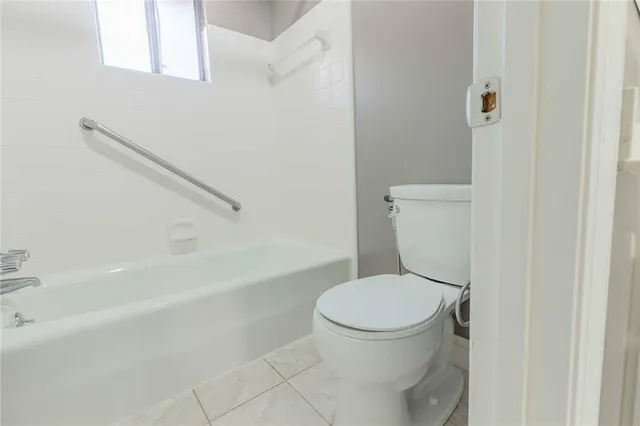 a white toilet sitting next to a bath tub