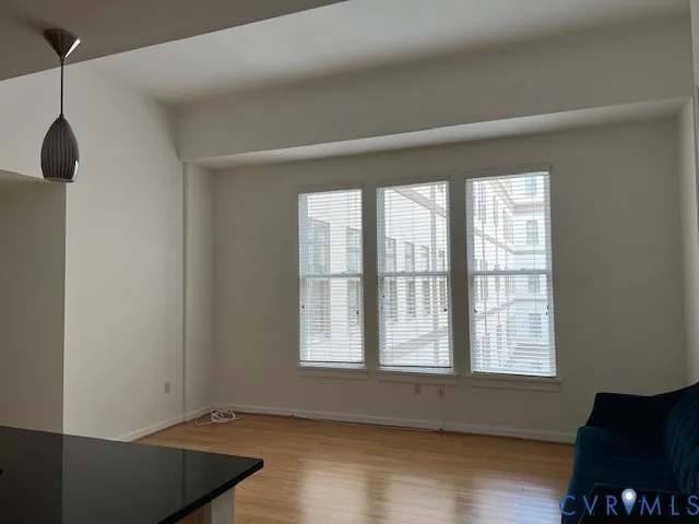 a view of an empty room with wooden floor and a window