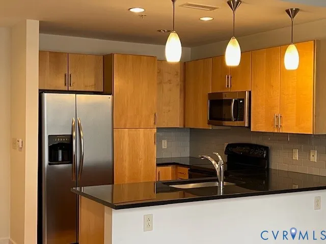 a kitchen with stainless steel appliances granite countertop a refrigerator a microwave a sink and a stove