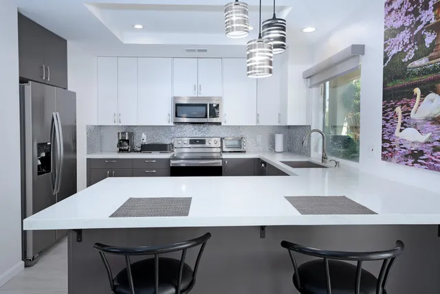 a kitchen with stainless steel appliances a table chairs microwave and refrigerator