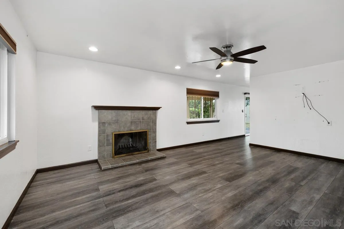 348 Sychar Road San Diego, CA 92114 - Photo 3 of 30 an empty room with wooden floor a fireplace and windows