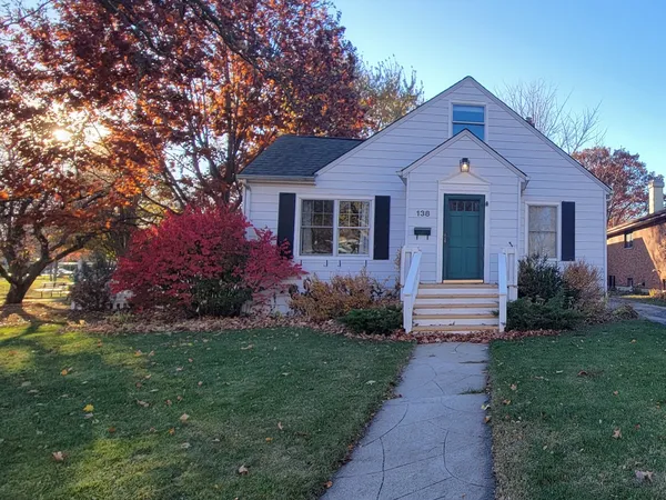 a front view of a house with a yard and trees