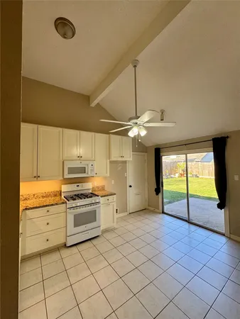an empty room with a chandelier fan and windows