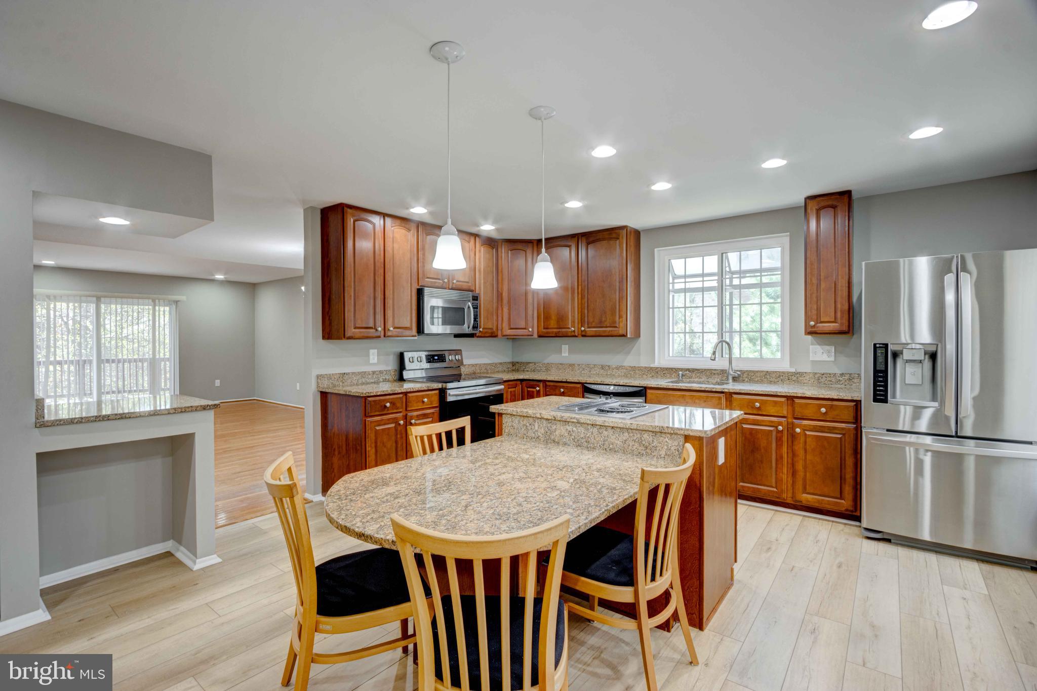 11859 Blue February Way Columbia, MD 21044 - Photo 11 of 35 a kitchen with stainless steel appliances granite countertop a kitchen island hardwood floor sink stove dining table and chairs