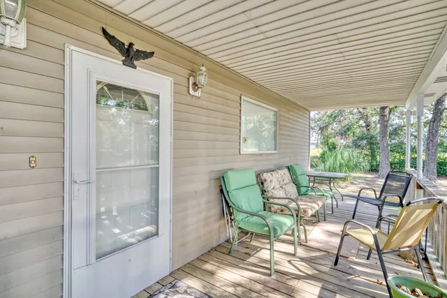 a view of a patio with table and chairs and couches with wooden floor and fence