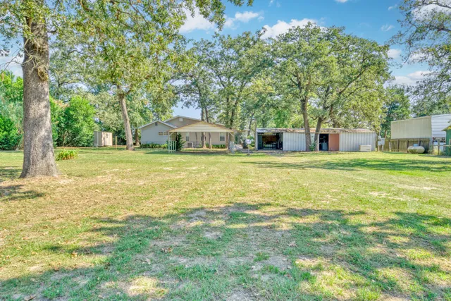 a view of a house with a big yard and large trees