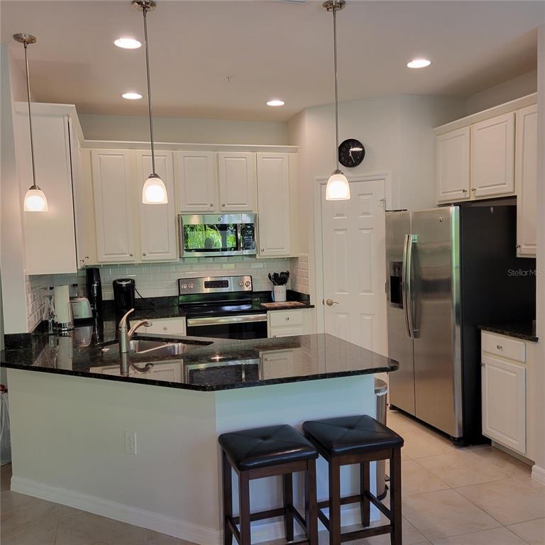 152 Navigation Circle, Unit 107 Osprey, FL 34229 - Photo 3 of 25 a kitchen with stainless steel appliances granite countertop a refrigerator a sink a stove a dining table and chairs