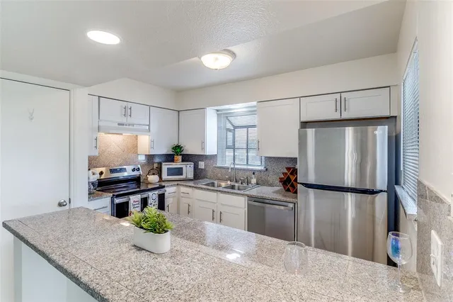 a kitchen with stainless steel appliances granite countertop sink stove and refrigerator