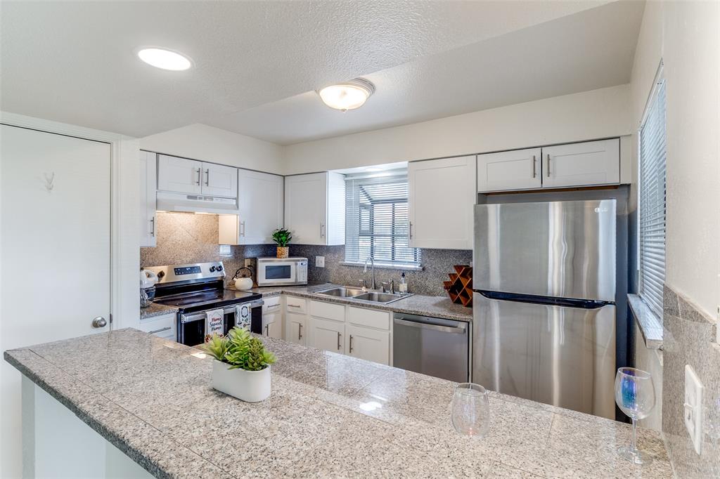 15151 Berry Trail, Unit 407 Dallas, TX 75248 - Photo 8 of 16 a kitchen with stainless steel appliances granite countertop sink stove and refrigerator