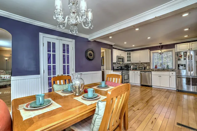 a open dining room with stainless steel appliances kitchen island granite countertop furniture and a dining table