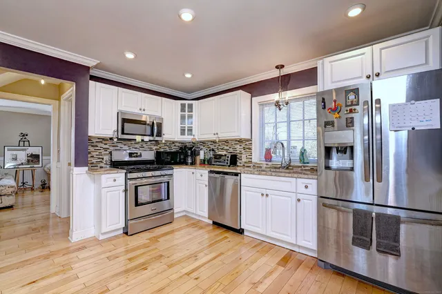 a kitchen with stainless steel appliances granite countertop a refrigerator a stove top oven a sink and dishwasher with wooden floor