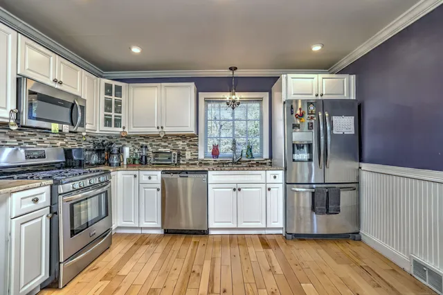 a kitchen with stainless steel appliances granite countertop a stove a sink and a refrigerator