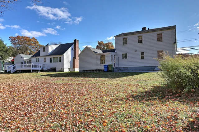 a view of a house with a large tree and a yard in front of it