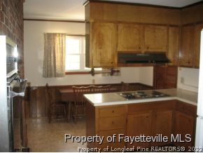 5322 Lakeview Road Hope Mills, NC 28348 - Photo 6 of 23 a kitchen with granite countertop a sink a stove and a wooden cabinets