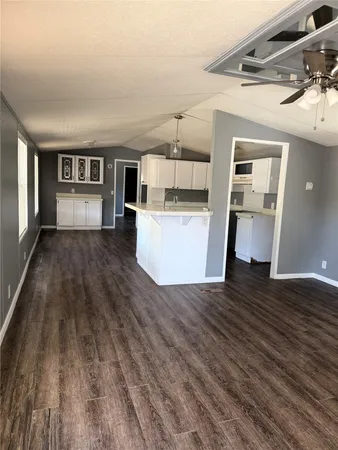 a view of empty room with wooden floor and kitchen view