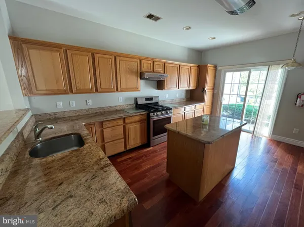 a kitchen with stainless steel appliances granite countertop a stove a sink dishwasher a microwave oven and a refrigerator with wooden floor