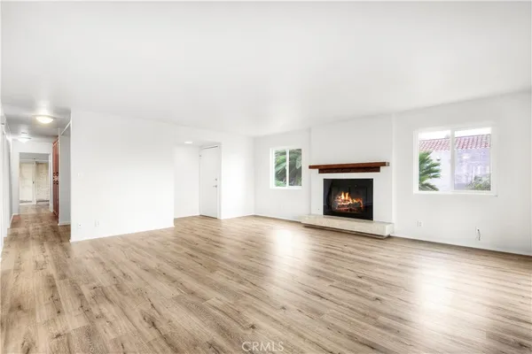 a view of an empty room with wooden floor fireplace and a window