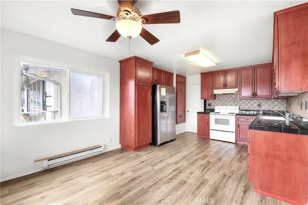 a kitchen with stainless steel appliances granite countertop a refrigerator a sink dishwasher a stove and white cabinets with wooden floor
