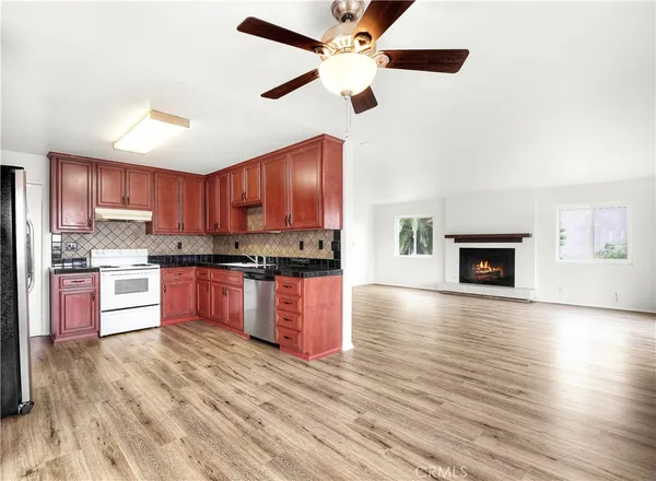 a large kitchen with granite countertop a stove top oven a sink dishwasher a dining table and chairs with wooden floor