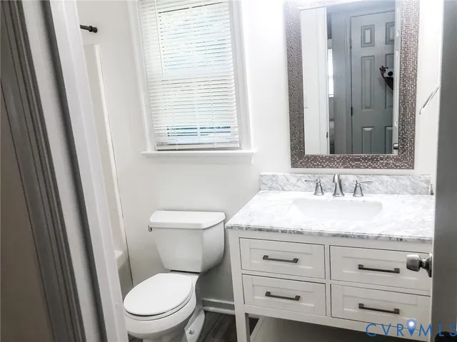 a bathroom with a granite countertop toilet sink and mirror