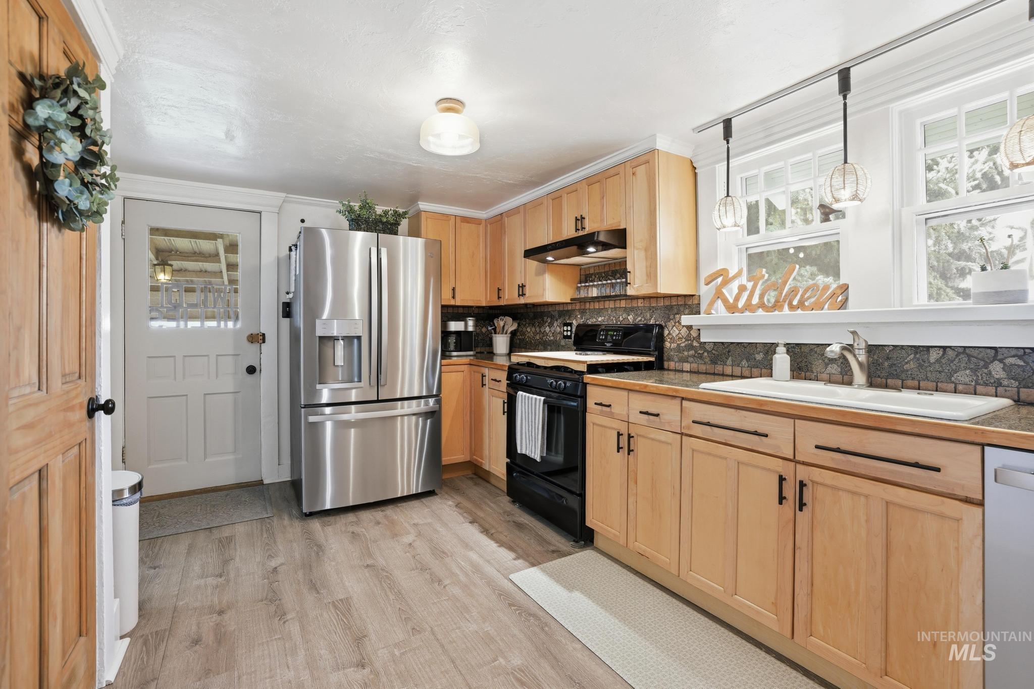 502 6th Street Filer, ID 83328 - Photo 15 of 41 Kitchen with stainless steel appliances, light wood finish cabinetry, light wood-type flooring, crown molding, and pendant lighting