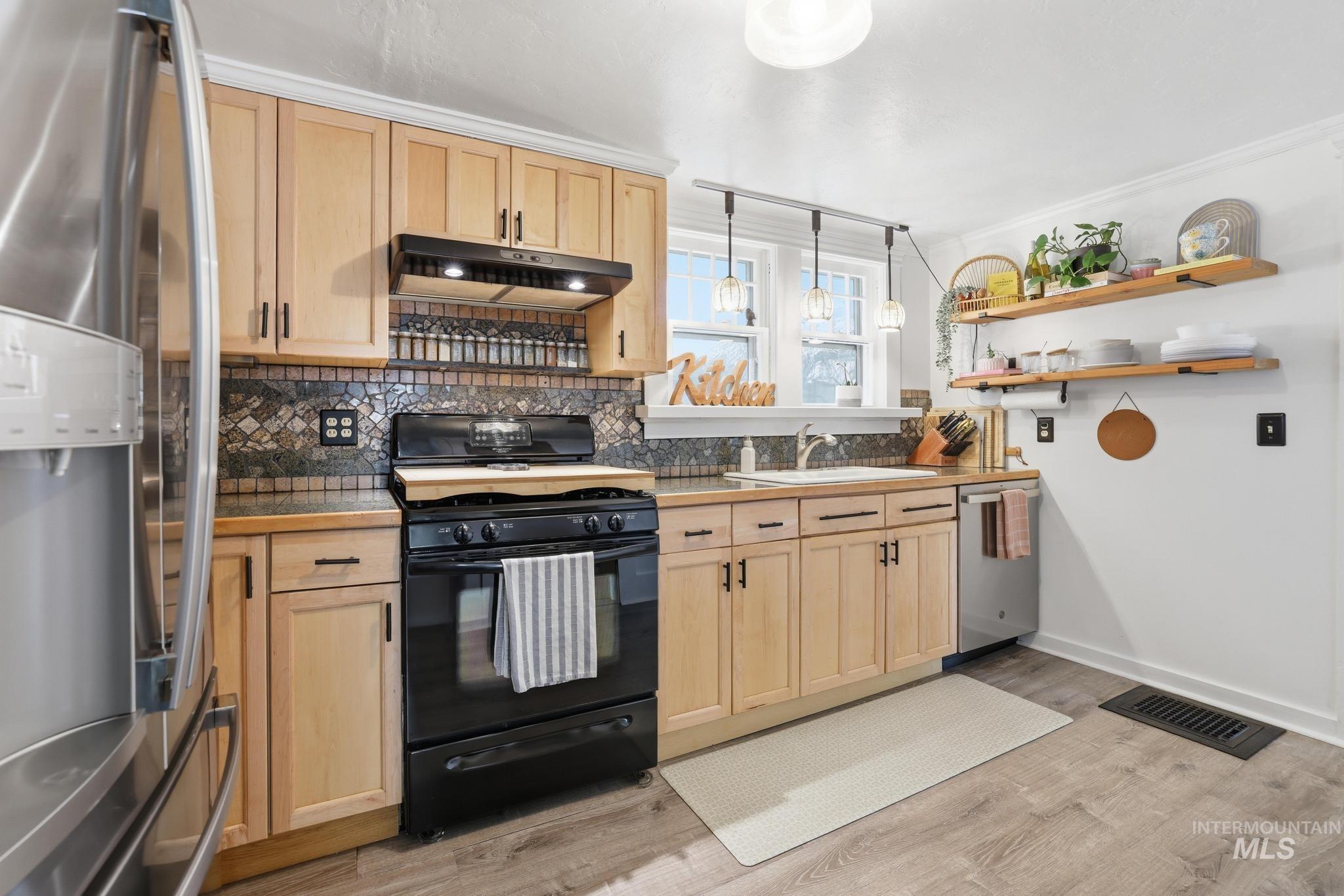 502 6th Street Filer, ID 83328 - Photo 16 of 41 Kitchen featuring stainless steel appliances, pendant lighting, light wood finish cabinetry, light wood finished floors, and crown molding