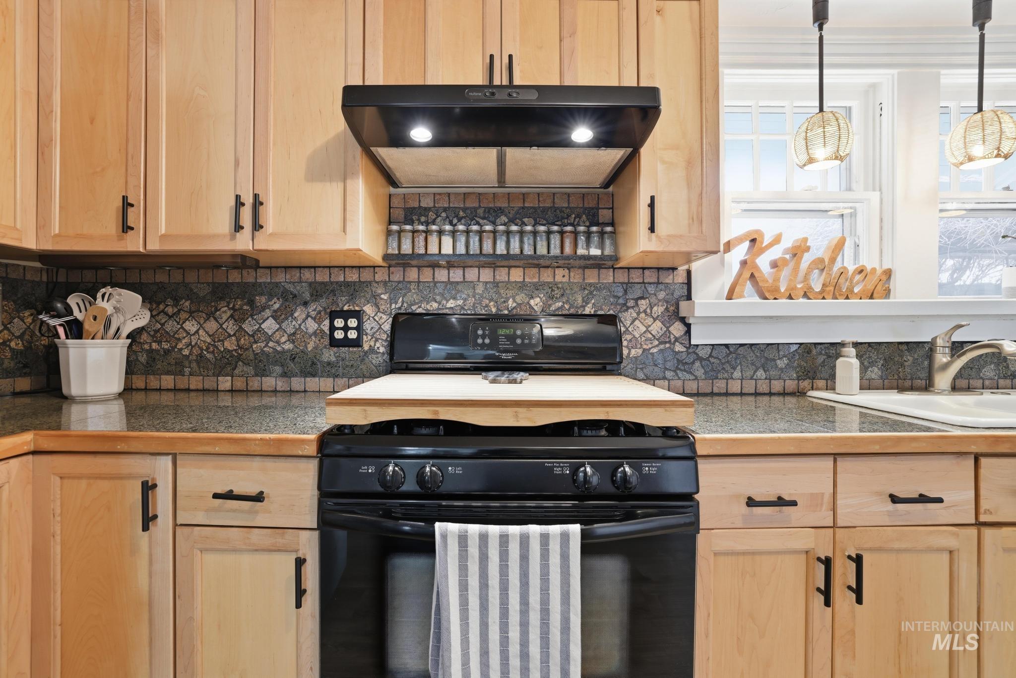 502 6th Street Filer, ID 83328 - Photo 17 of 41 Kitchen featuring black range, light wood finish cabinets, decorative backsplash, extractor fan, and decorative light fixtures