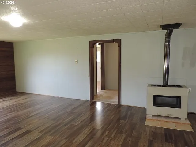 a view of an empty room with wooden floor and a fireplace