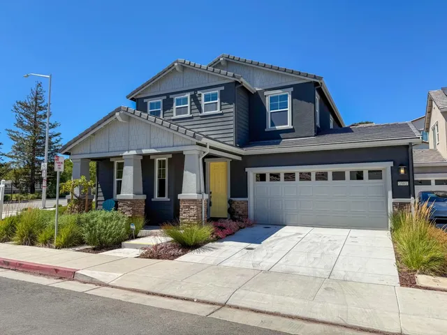a front view of a house with a yard and potted plants