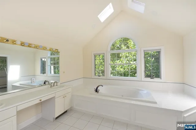 a bathroom with a granite countertop tub a sink and a window