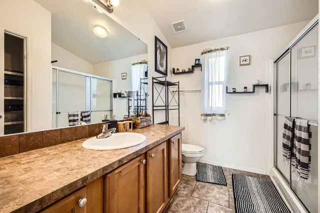 a bathroom with a granite countertop sink a toilet a mirror and shower