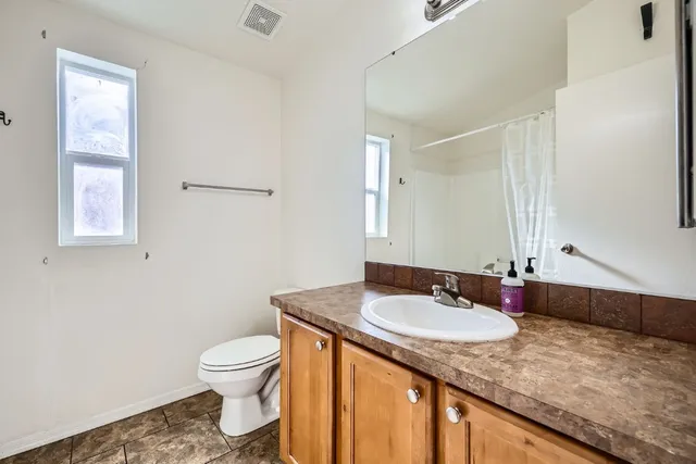 a bathroom with a granite countertop sink a toilet and a mirror