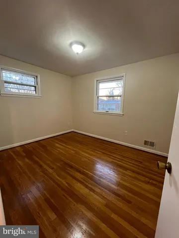 a view of an empty room with wooden floor and a ceiling fan