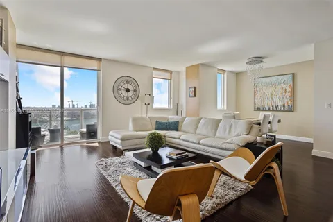a living room with furniture a large window and wooden floor