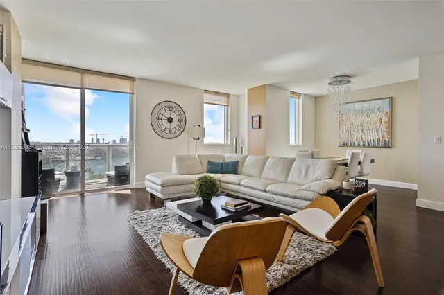 a living room with furniture a large window and wooden floor