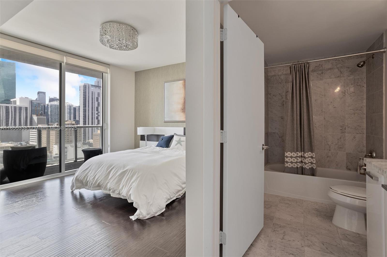 244 Biscayne Boulevard, Unit 1803 Miami, FL 33132 - Photo 27 of 38 a bedroom with a large bed and a chandelier