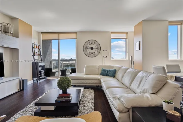 a living room with furniture a clock on wall and a window