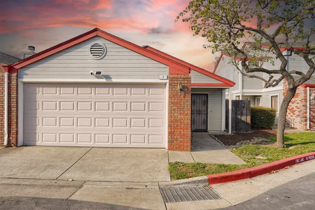 a view of a house with a small yard plants and large tree