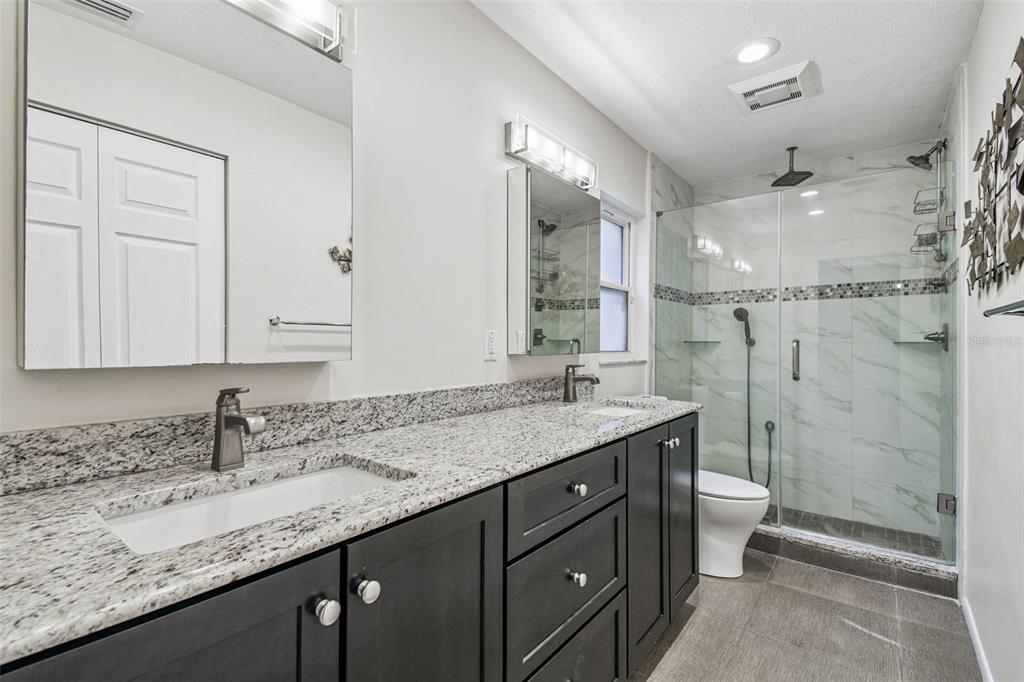 4161 Rolling Springs Drive Tampa, FL 33624 - Photo 26 of 52 a bathroom with a granite countertop sink a toilet a mirror and shower